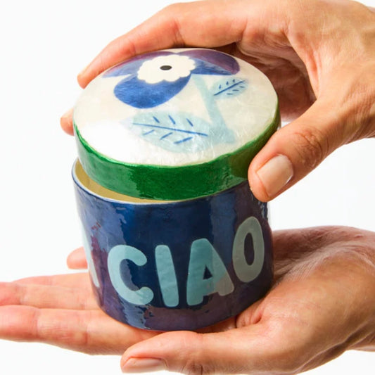 Ceramic container with 'CIAO' text held by a hand on a white background