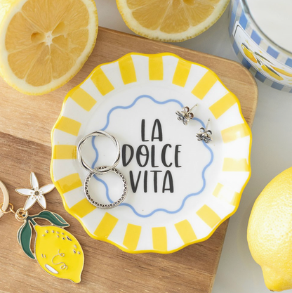 Yellow and white decorative plate with 'La Dolce Vita' text, surrounded by lemons and keychains.