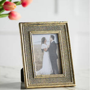 Gold photo frame with a picture of a couple on a marble surface with tulips in the background