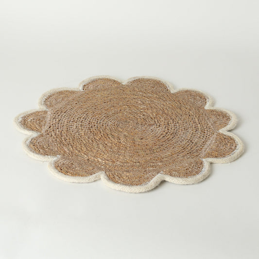 A round woven placemat with a scalloped edge, made from natural tan jute in the center and cream-colored trim around the border, shown on a white background.