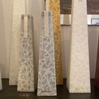 A set of sculptural candles with gray marbled patterns, labeled 'Black Iris', placed on a wooden surface.