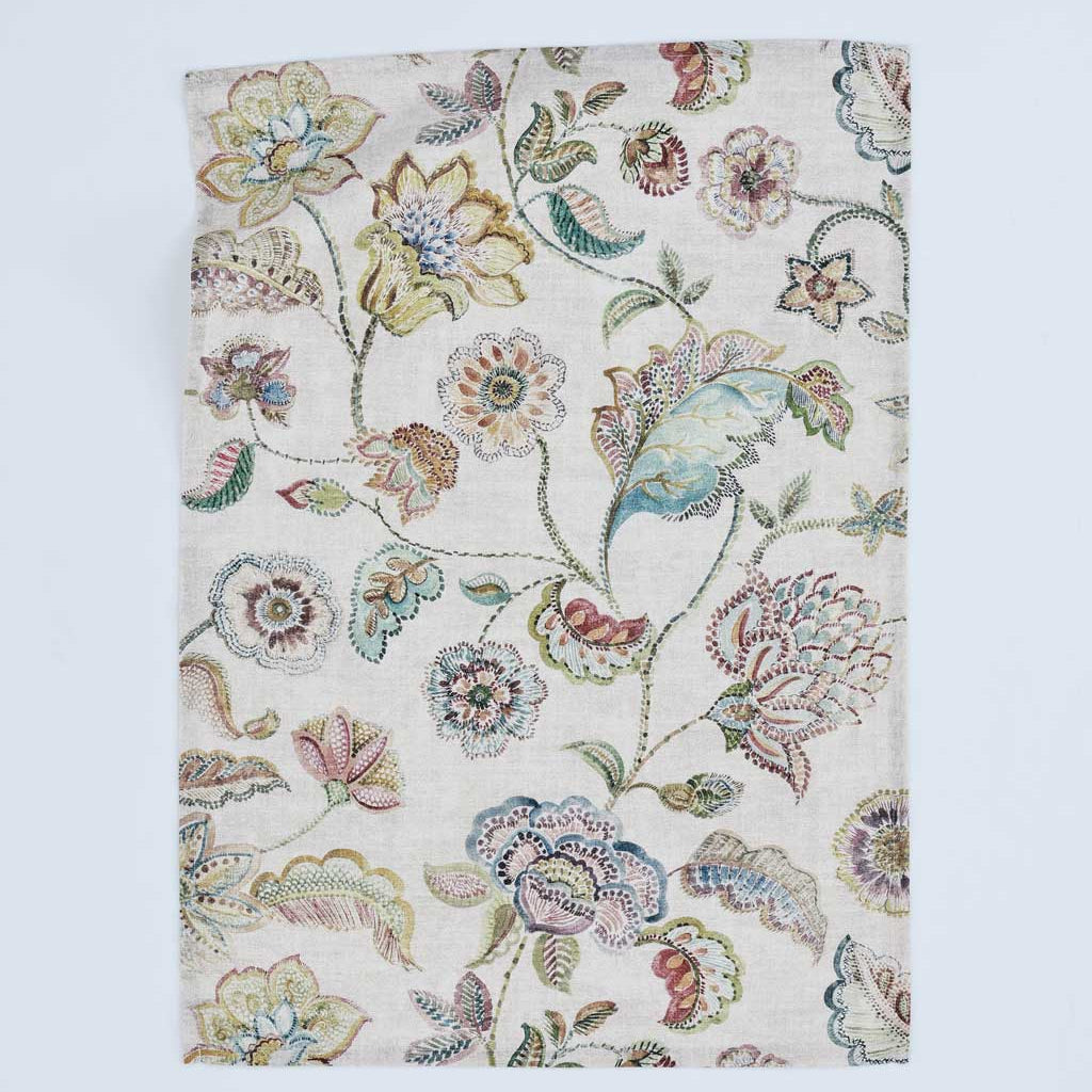 A rectangular fabric panel or napkin featuring an intricate vintage floral and botanical pattern in muted pastel colors on a cream background, displayed flat against a light gray backdrop.