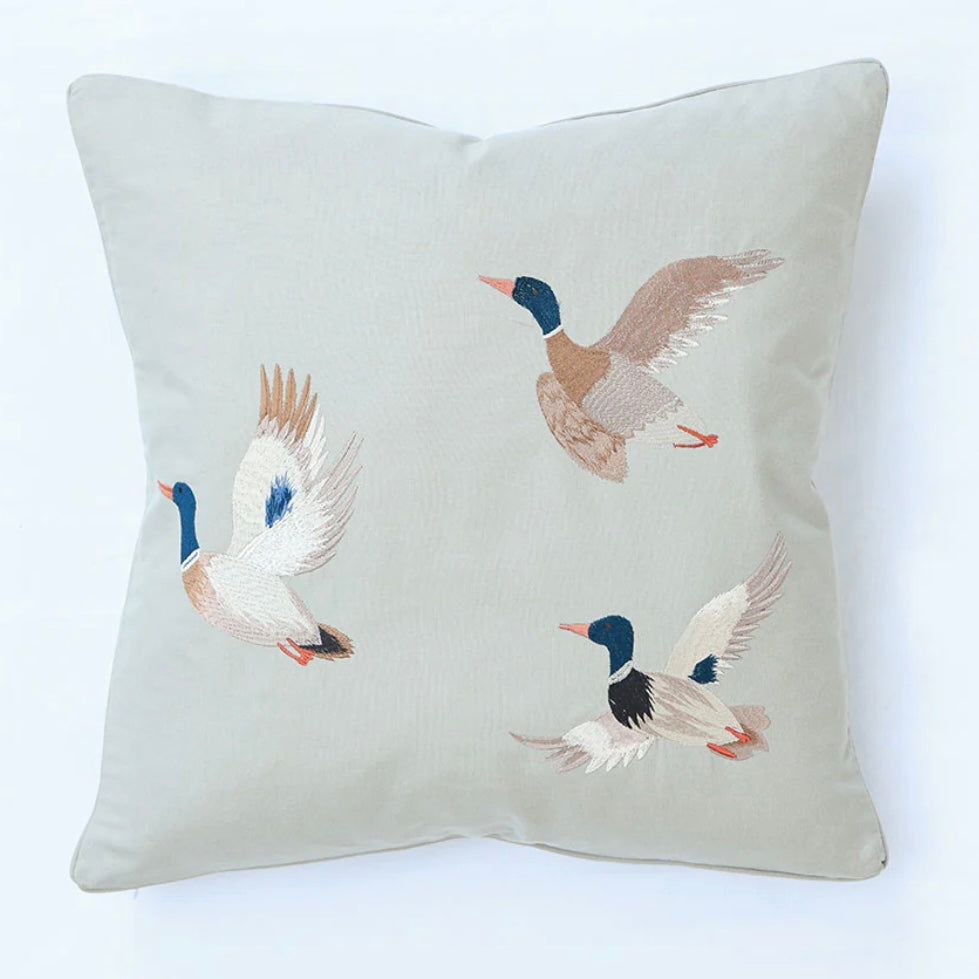 Decorative pillow with embroidered ducks on a light background
