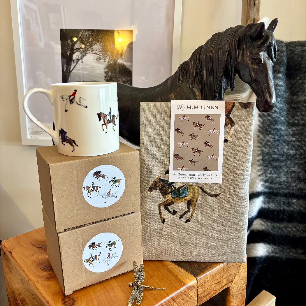 A white bone china mug with equestrian sport designs, displayed alongside its packaging which has similar design elements.