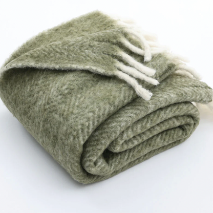 Folded green blanket with white tassels on a white background
