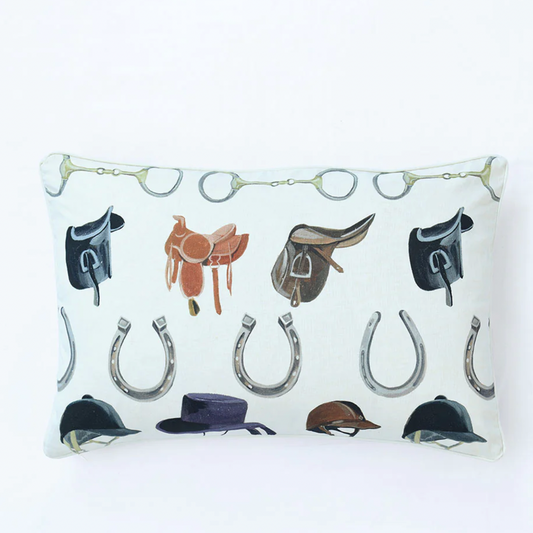 Decorative pillow with equestrian-themed design featuring saddles, hats, and horseshoes on a white background.