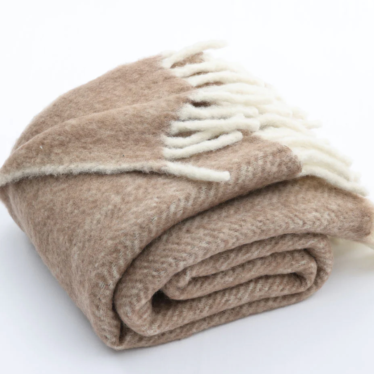 Folded beige blanket with white fringe on a white background