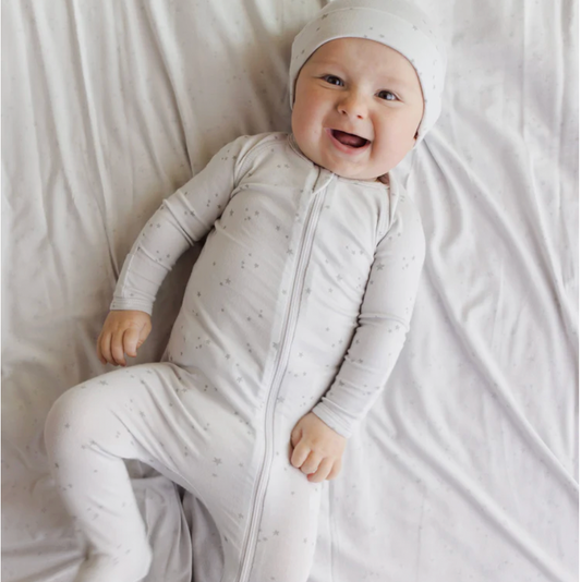 Baby in a light gray onesie with a hood on a white blanket