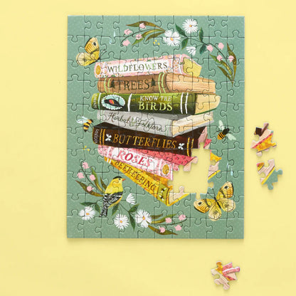 Jigsaw puzzle with book and nature-themed design on a yellow background