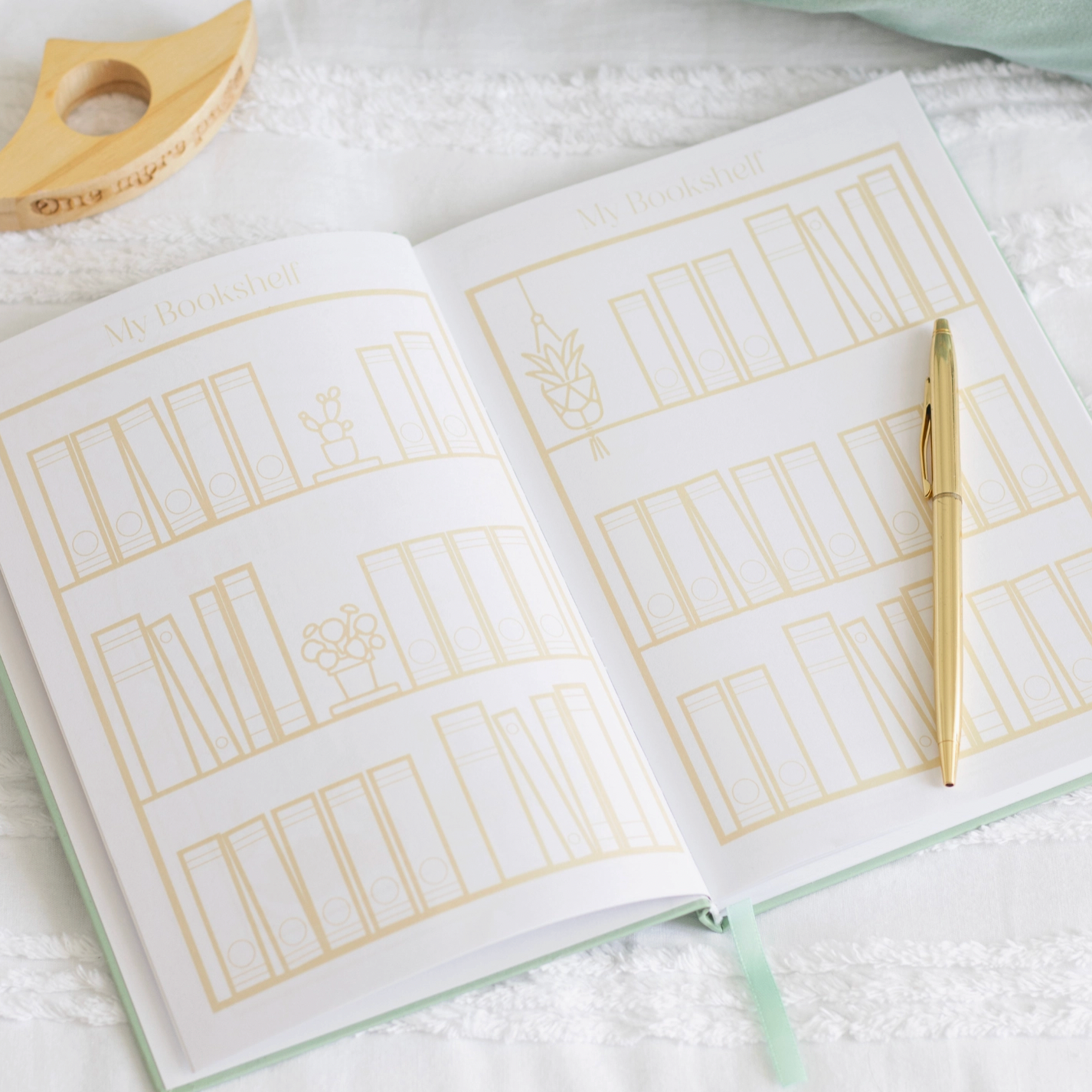 Open notebook with gold line art on a white surface, accompanied by a gold pen.