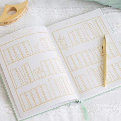 Open notebook with gold line art on a white surface, accompanied by a gold pen.