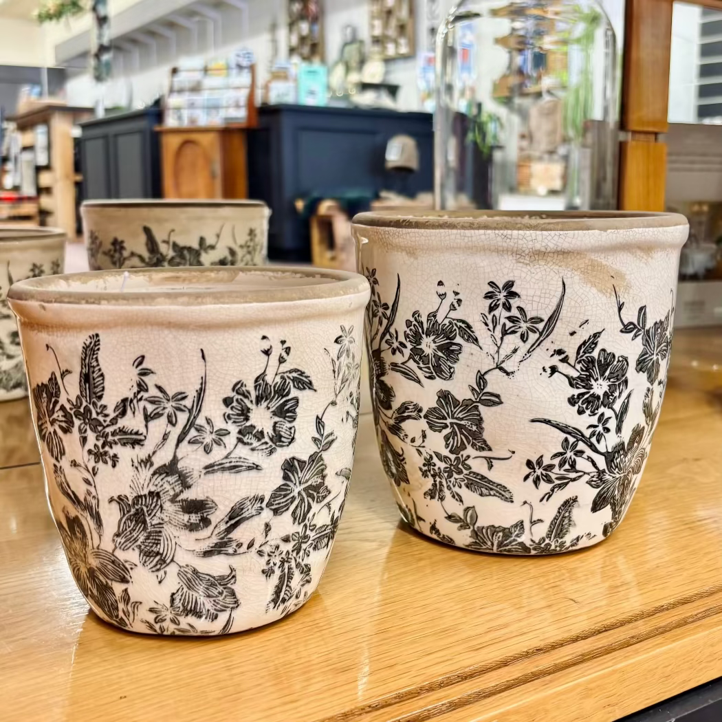 Three ceramic pots with floral patterns on a wooden surface.