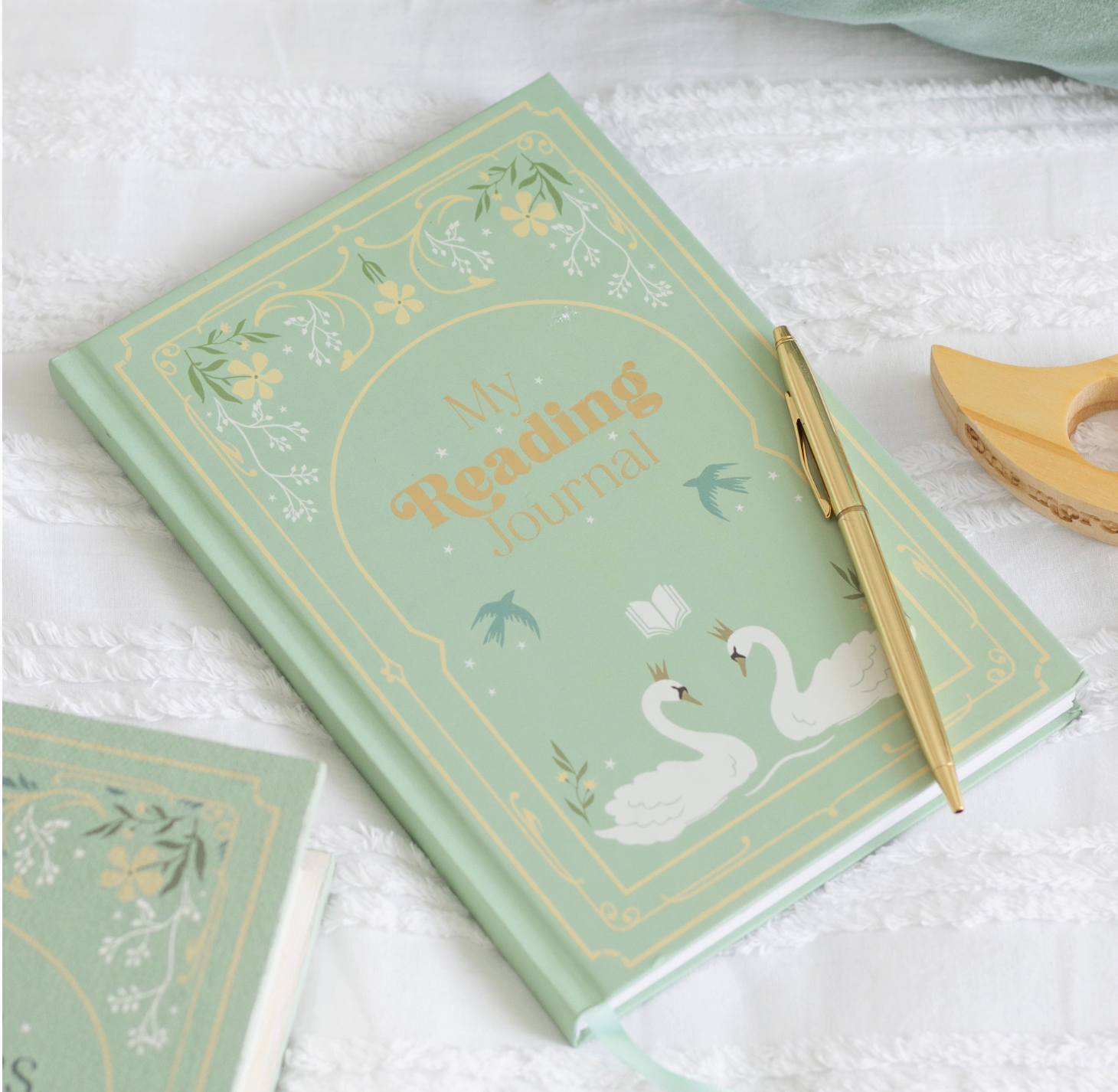 Decorative notebook with swan design and gold text on a white surface
