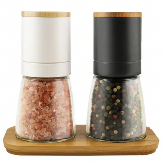 Two salt and pepper shakers on a wooden base with a white background