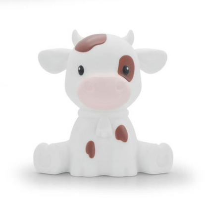 A small white cow figurine with brown spots, a pink snout, and black eyes, sitting against a plain white background.