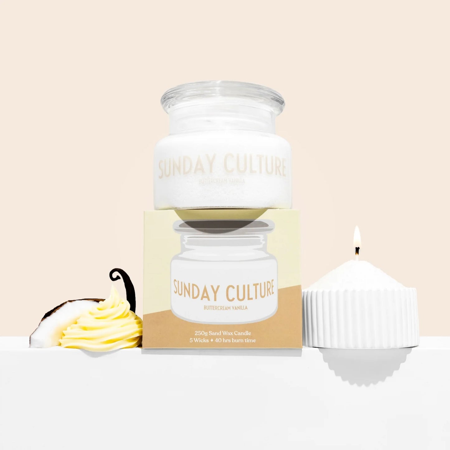 Sunday Culture Buttercup Candle set featuring a white wax jar with a clear glass lid, a kraft paper box, and a white cupcake-shaped candle on a light beige background.