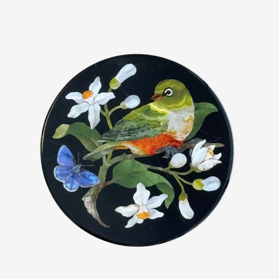 Decorative coaster with a bird and floral design on a black background
