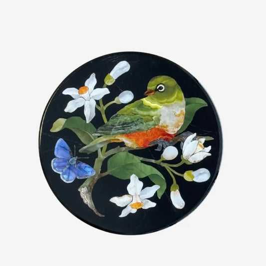 Decorative coaster with a bird and floral design on a black background