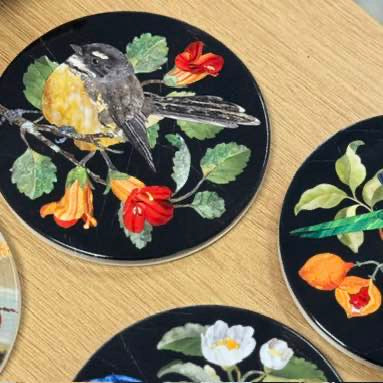 Decorative coasters with bird and floral designs on a wooden surface