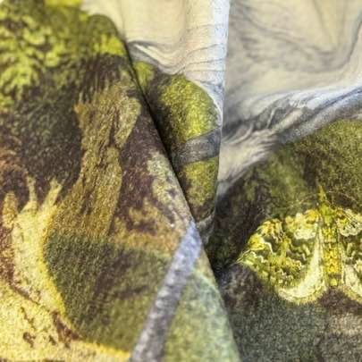 Close-up of the heron microfibre tea towel fabric with green, brown, and gray patterns.