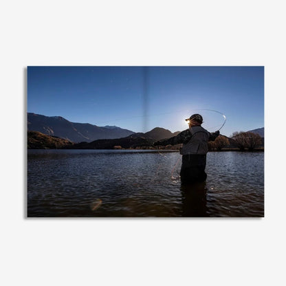 Person fly fishing in a lake with mountains in the background