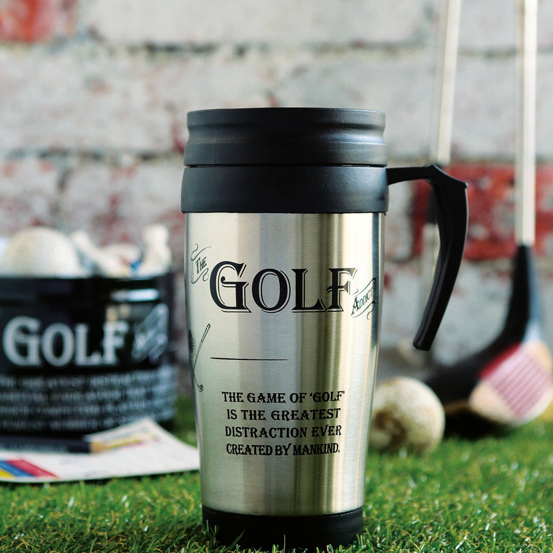 A stainless steel travel tumbler with a black lid and handle, featuring a golf-themed design with the word 'GOLF' and a quote by Mark Zuckerberg, set on artificial grass with golf props in the background.