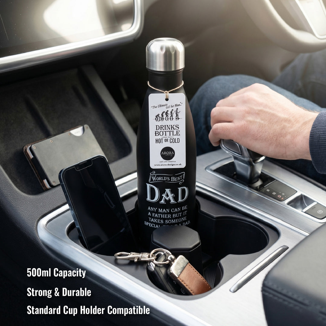 Bottle labeled 'World's Best Dad' in a car cup holder with phone and keychain.