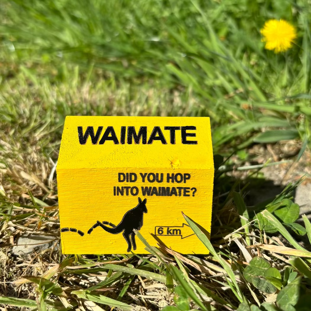 Yellow sign with 'Waimate' and wallaby illustration on grass