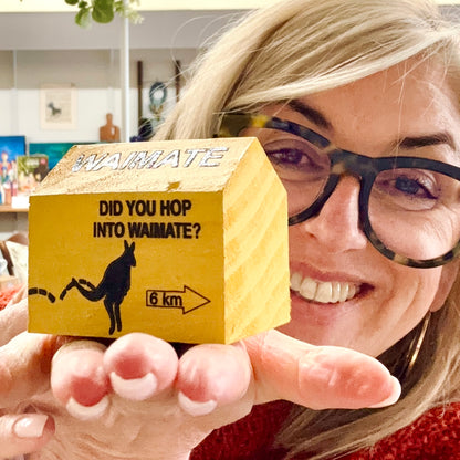 Person holding a small wooden box with 'Waimate' branding and text.