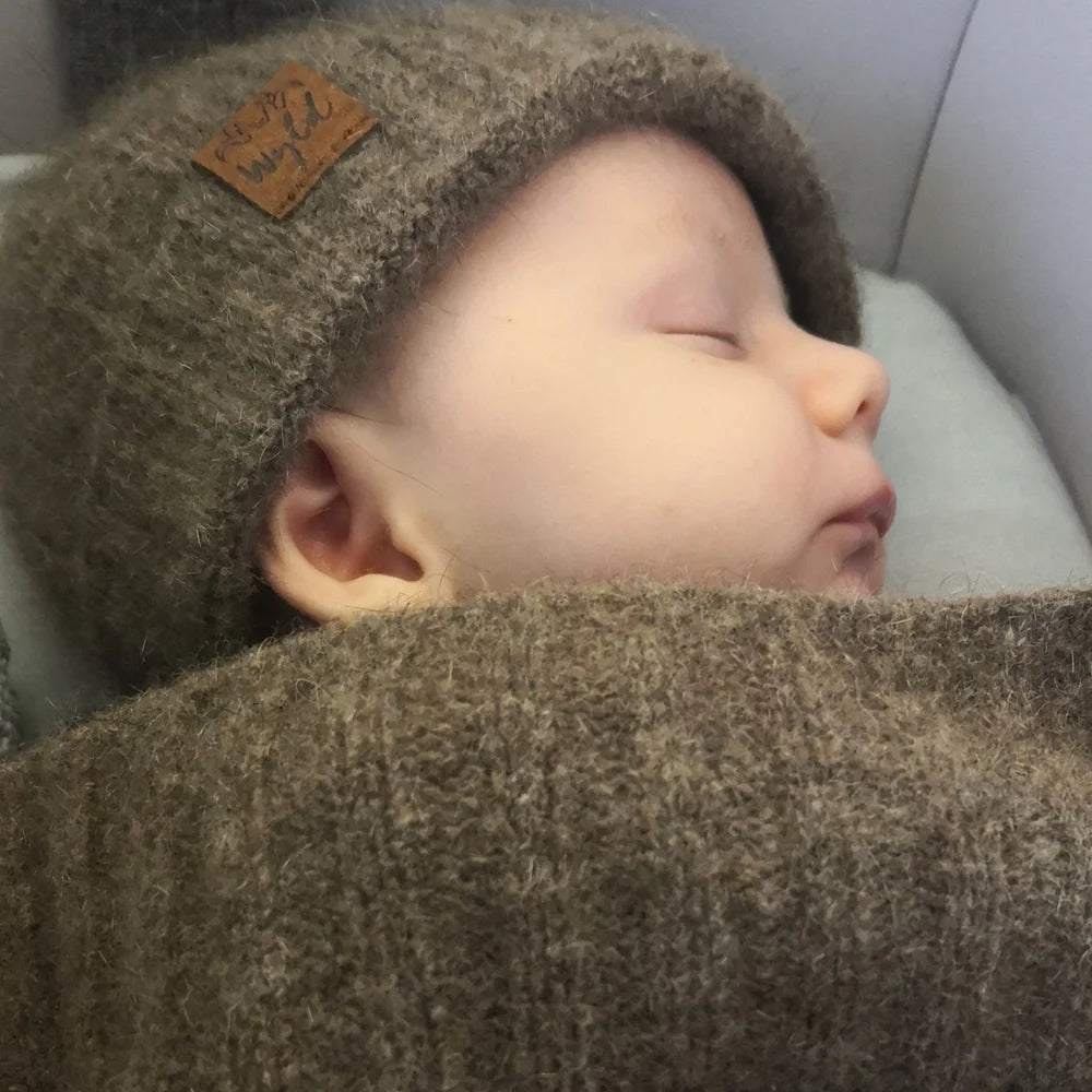 Child sleeping with a brown knit hat and matching blanket