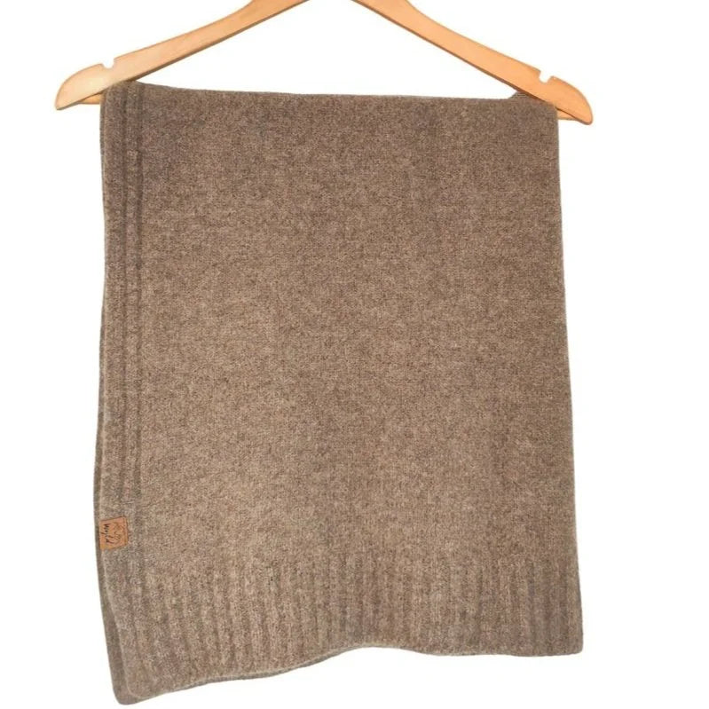 A brown knit blanket or throw hanging from a wooden hanger against a plain white background.