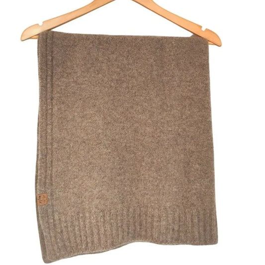 A brown knit blanket or throw hanging from a wooden hanger against a plain white background.