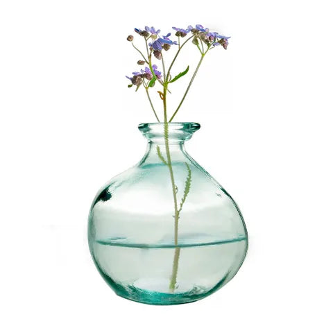 A clear glass vase with a rounded bulbous body and narrow neck, partially filled with water, holding a single stem of small purple flowers against a white background.