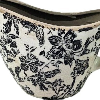 Ceramic gravy boat with black floral pattern on a white background
