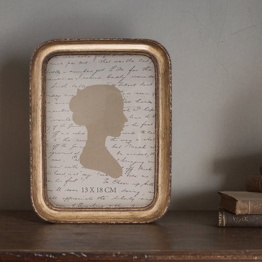 Framed silhouette art on a shelf with books and a candle