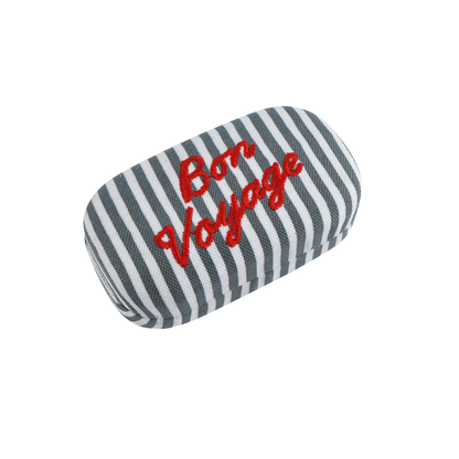 A gray and white striped fabric case with red embroidered text reading 'Bon Voyage' on a plain white background.