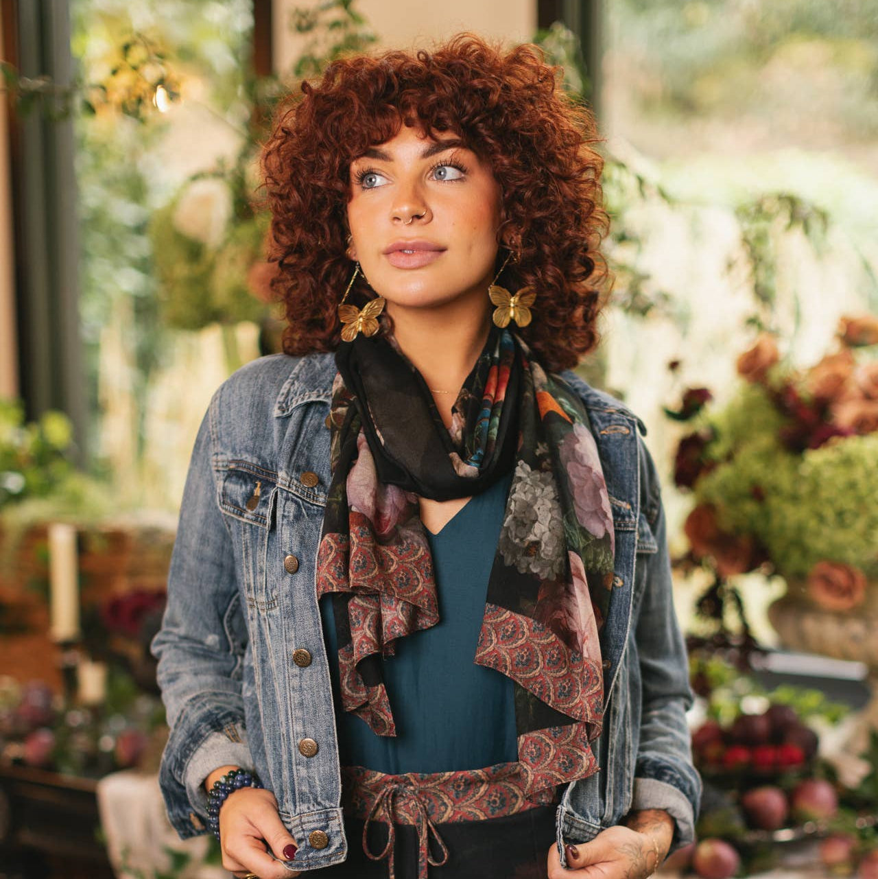 Woman wearing a denim jacket and floral outfit in a garden setting