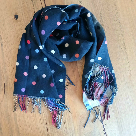 Navy blue scarf with colorful polka dots and fringe on a wooden surface