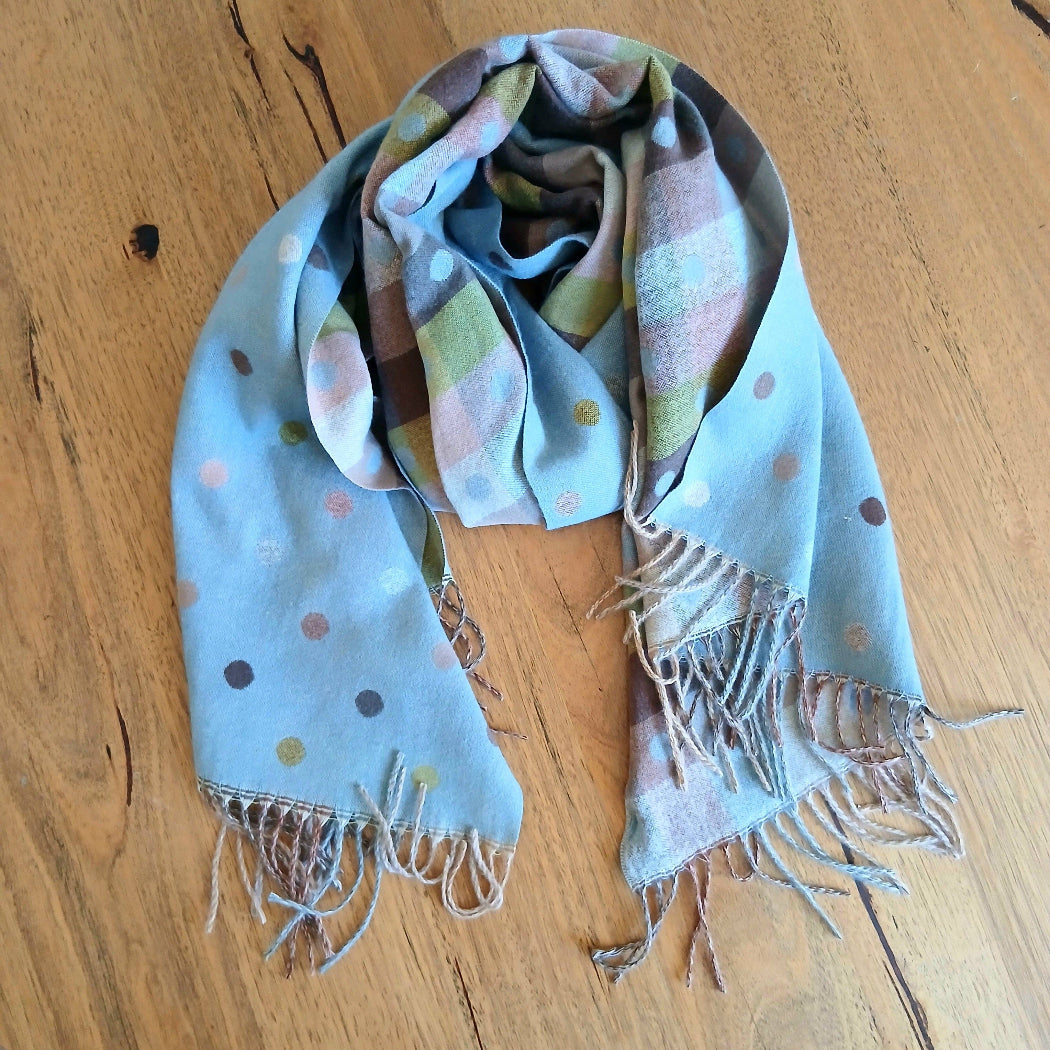 Colorful scarf with polka dots and fringes on a wooden surface