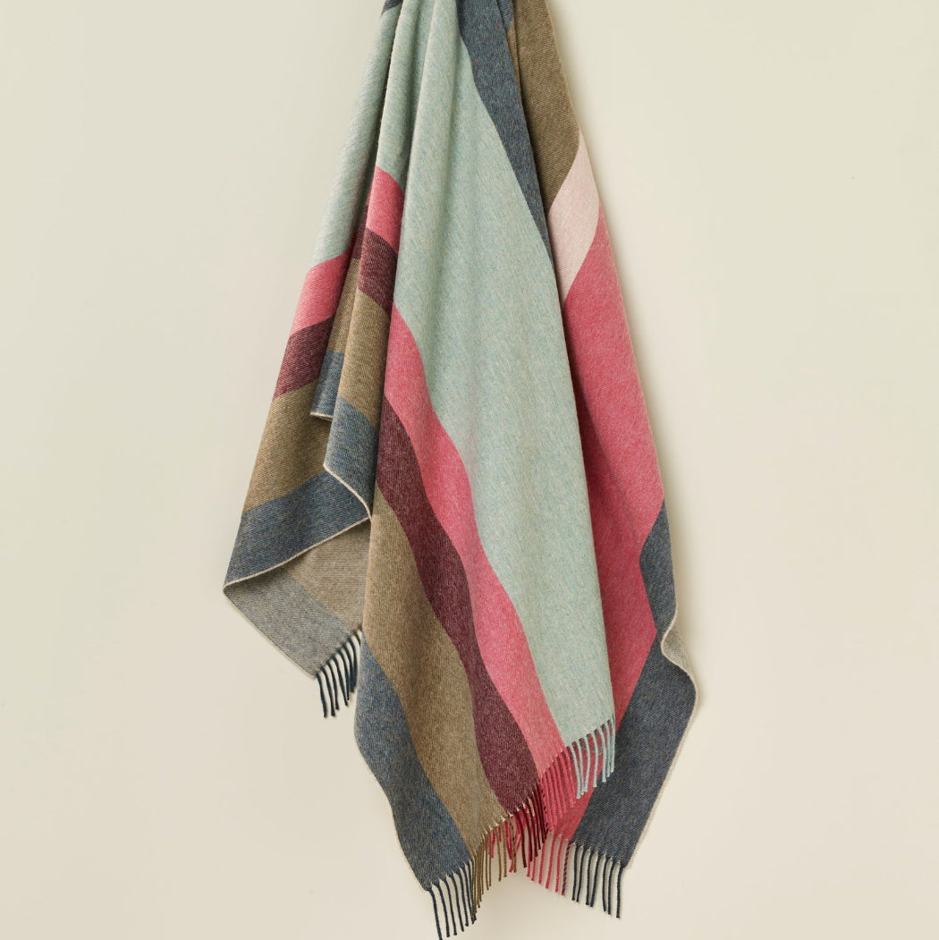 Colorful striped blanket draped over a chair on a beige background
