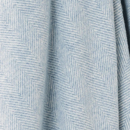 A close-up of a light blue and white herringbone patterned fabric with soft folds.