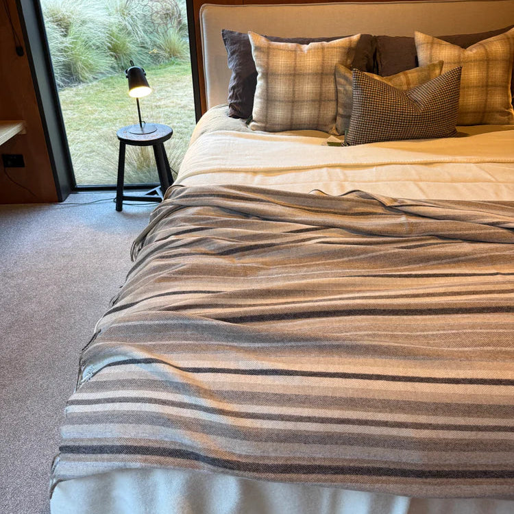 Bedroom with a large bed, striped bedding, and plaid pillows near a window.