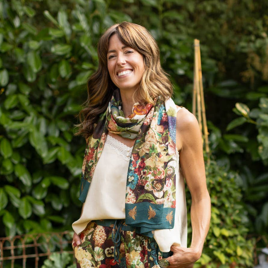 Woman in a garden wearing floral pants and a scarf