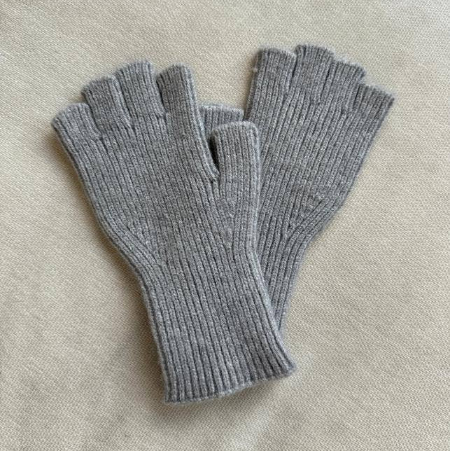 Pair of gray fingerless gloves on a light beige fabric background
