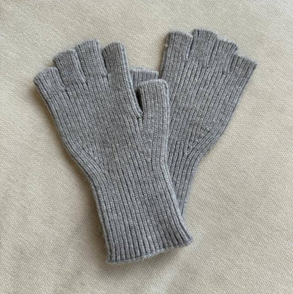 Pair of gray fingerless gloves on a light beige fabric background
