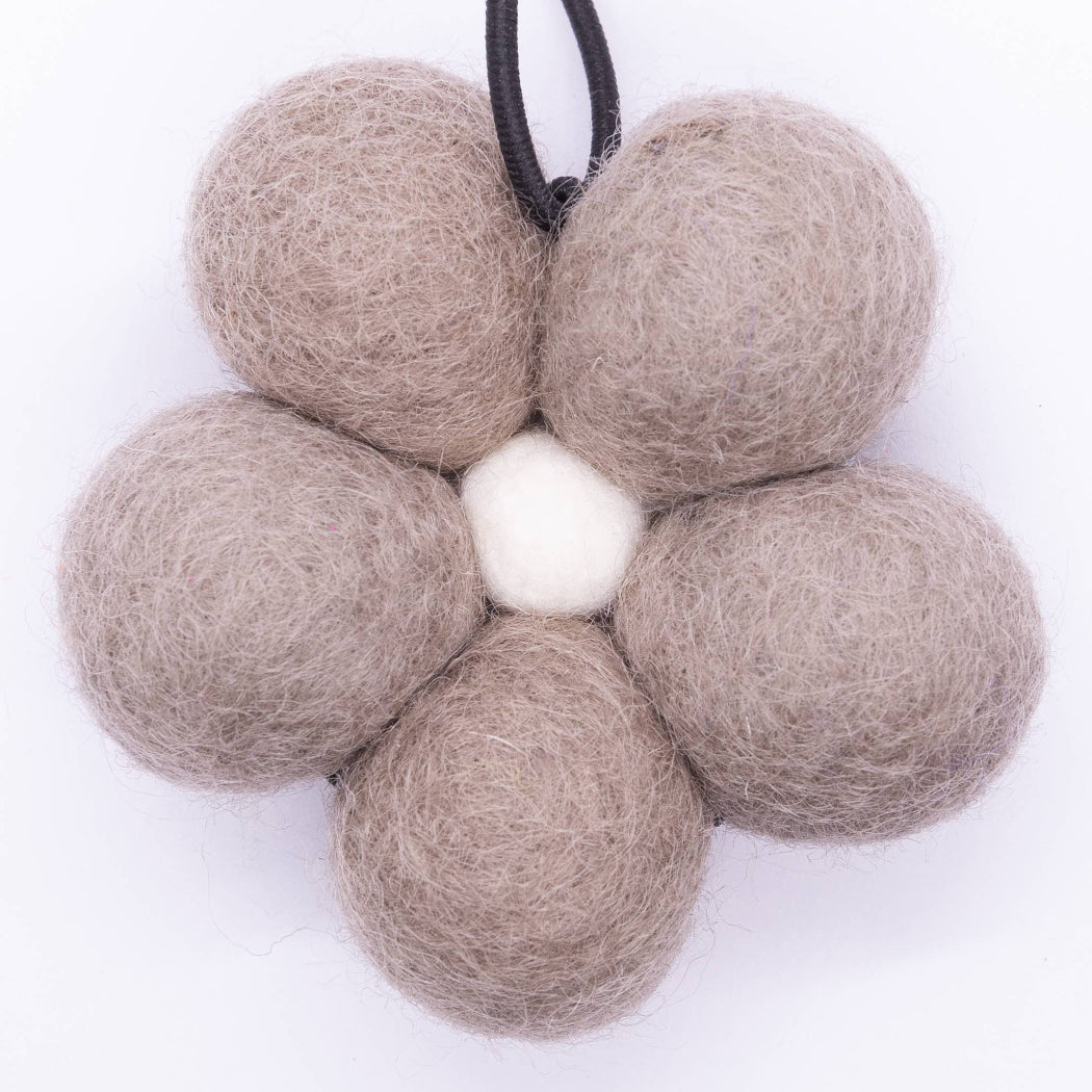 Flower-shaped arrangement of beige felt balls on a white background