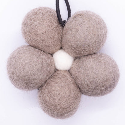 Flower-shaped arrangement of beige felt balls on a white background