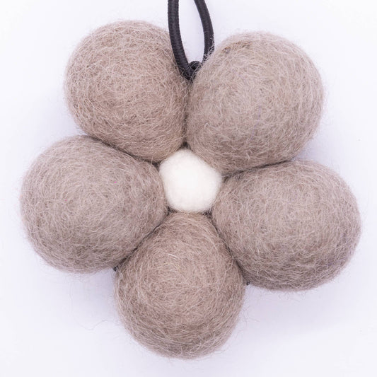 Flower-shaped arrangement of beige felt balls on a white background