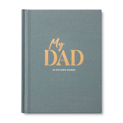 A hardcover journal with a textured slate blue-gray cover, featuring the title 'My DAD' in gold foil lettering and the subtitle 'IN HIS OWN WORDS' in white, shown on a clean white background.