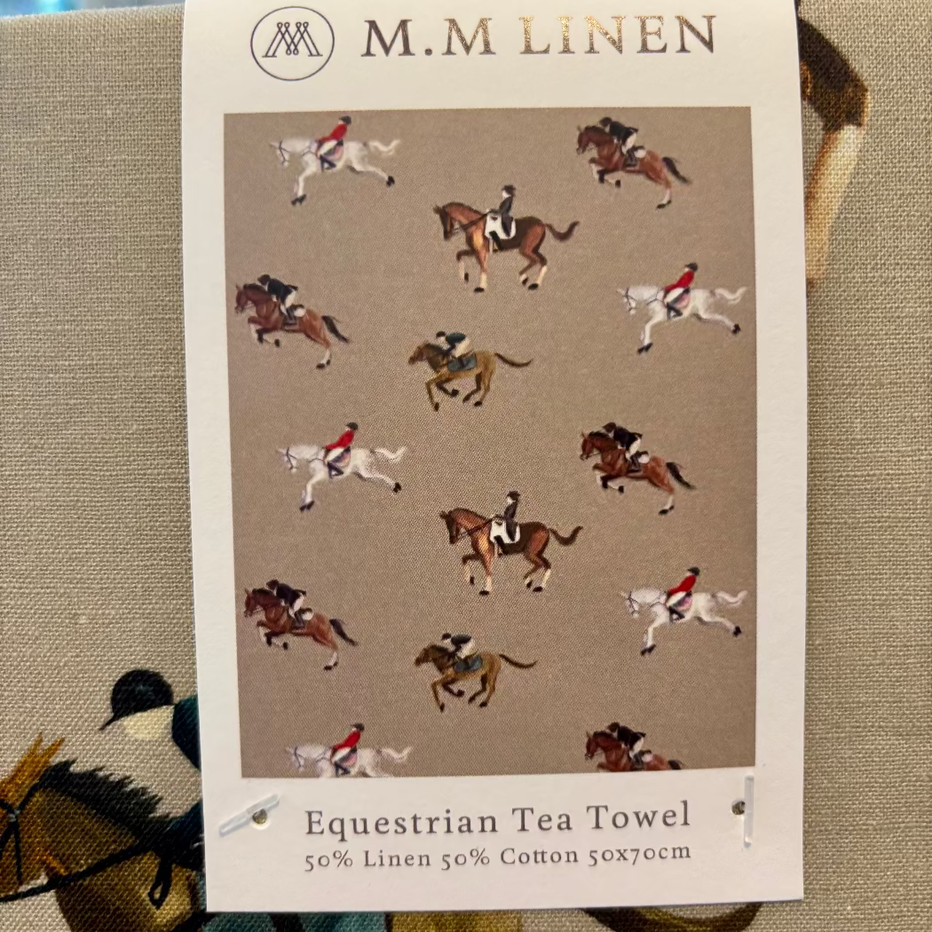 M.M Linen equestrian-themed tea towel with horse and jockey pattern on a beige background.